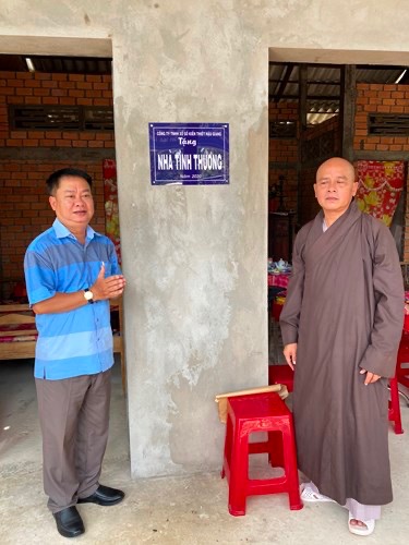 Two people standing in front of a buildingDescription automatically generated