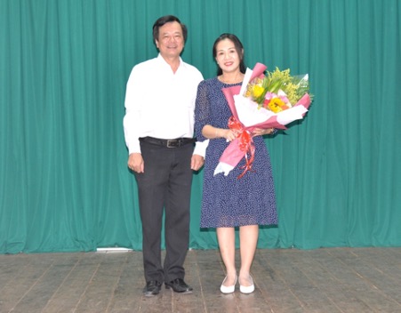 Two people standing in front of a curtainDescription automatically generated